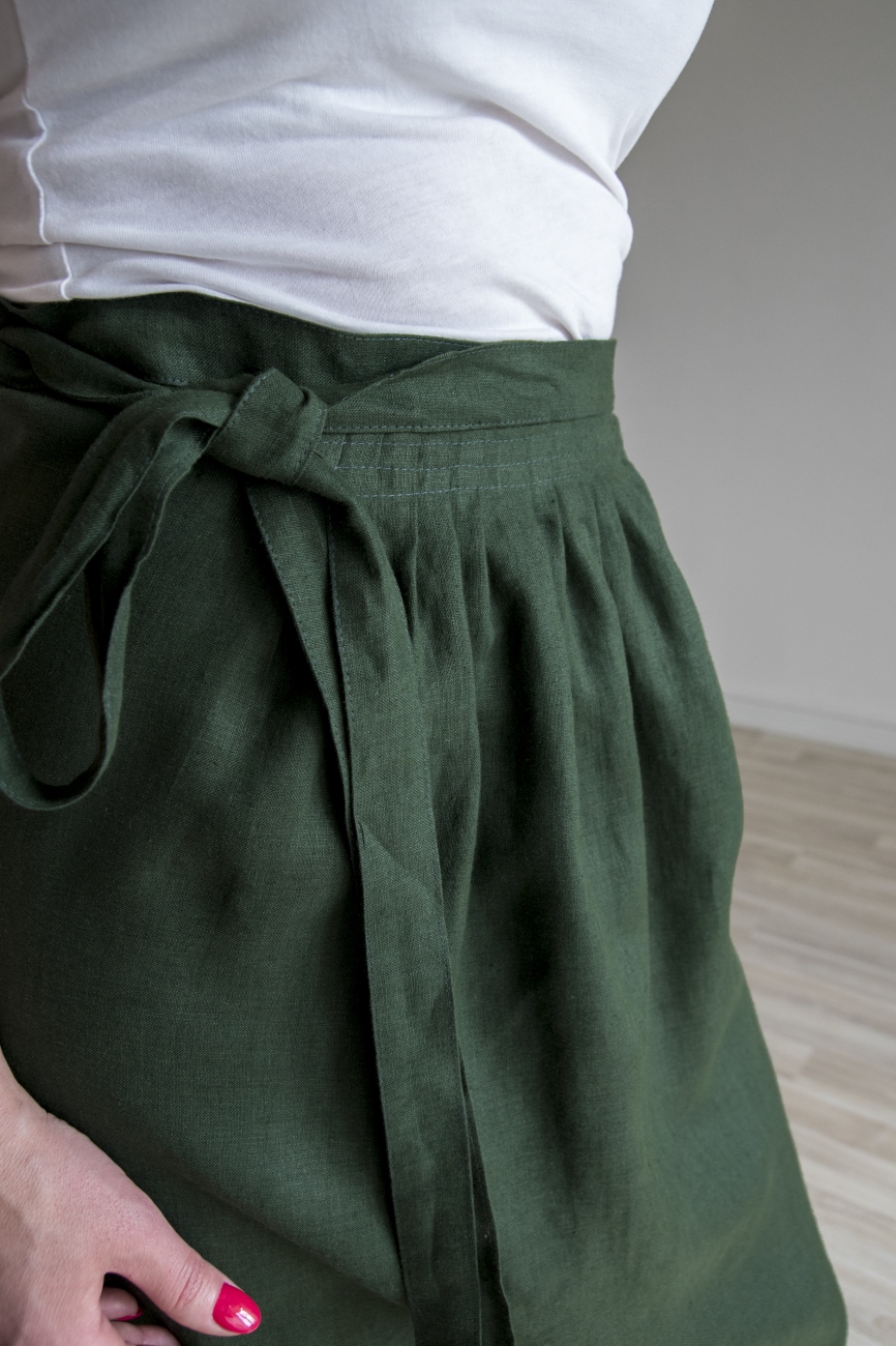 Dark green washed linen half apron with adjustable width and a pocket